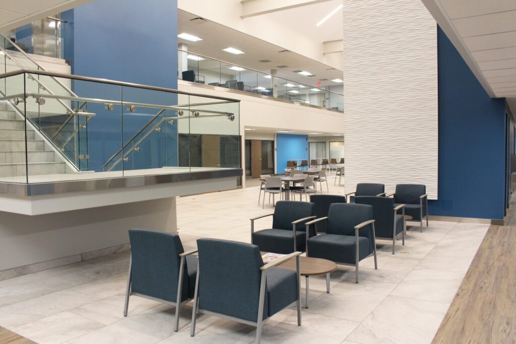A beautiful glass staircase and blue chairs are showcased in the lobby of the McLaren St. Luke’s Fallen Timbers Medical Building